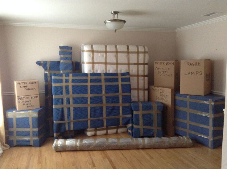 alt="Living room with all furniture wrapped in blankets for protection during a move"